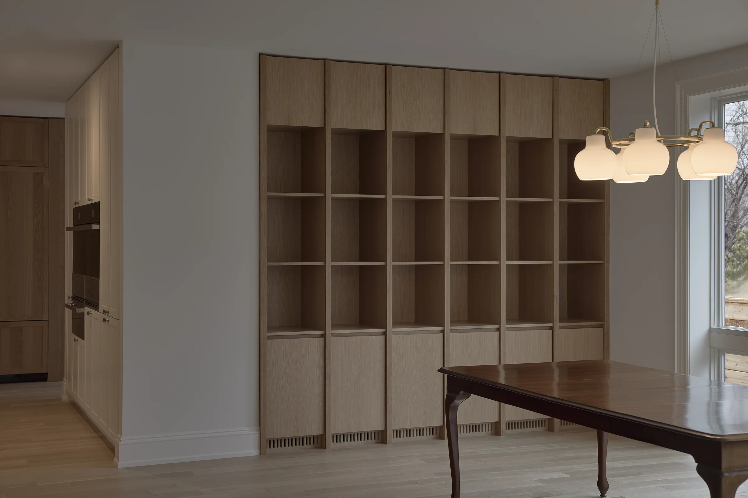 Woodlawn dining room framed by custom oak shelving and pendant lights