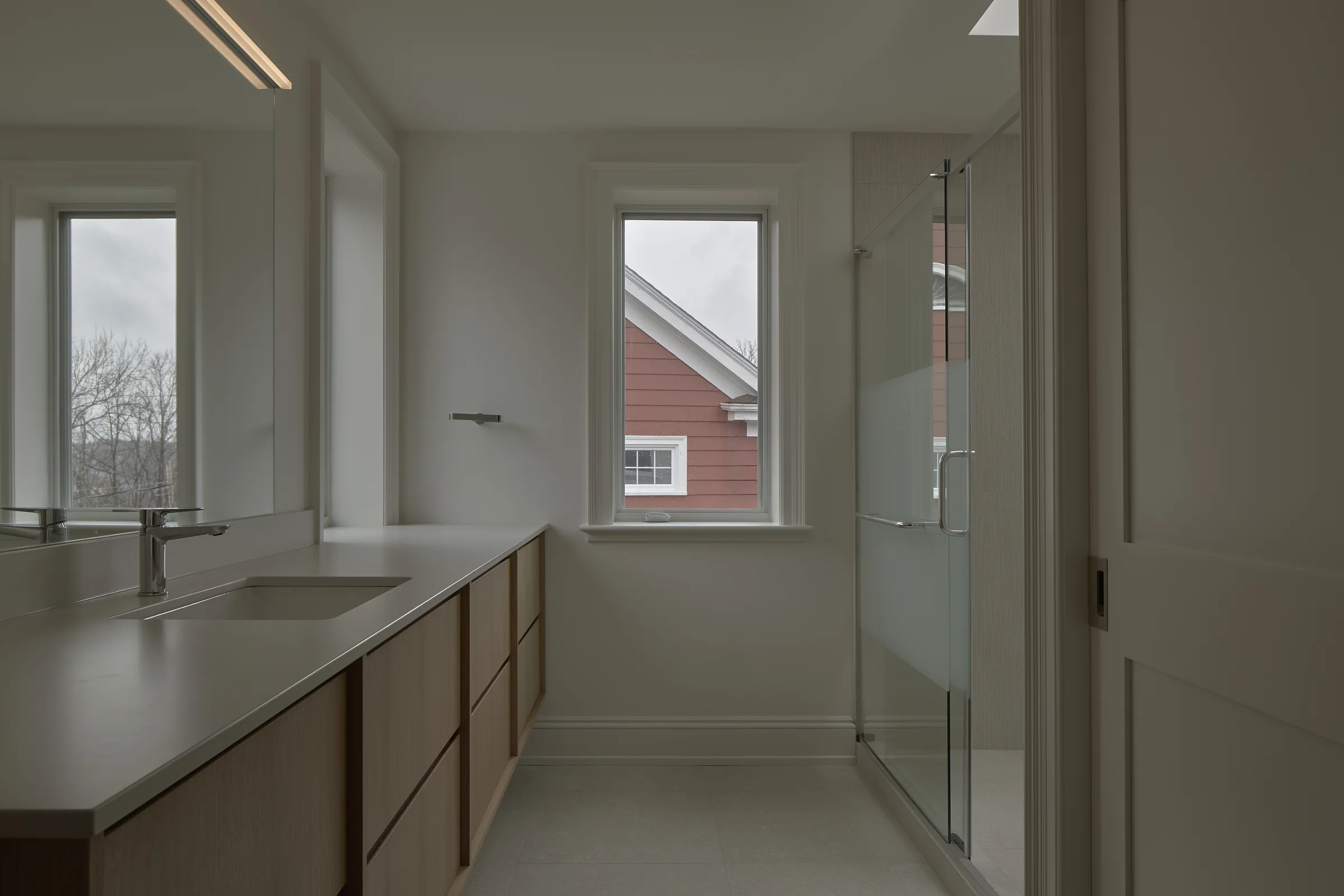 Long oak vanity leading into a glass shower at Woodlawn