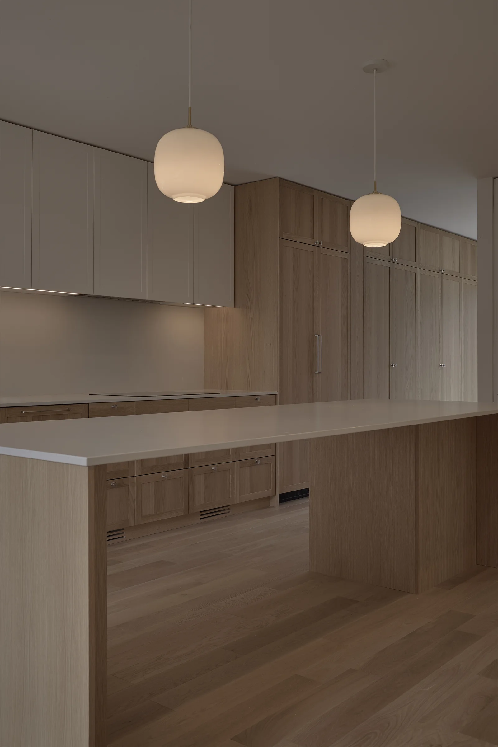Pale oak Woodlawn kitchen with stone counters and globe pendant lights